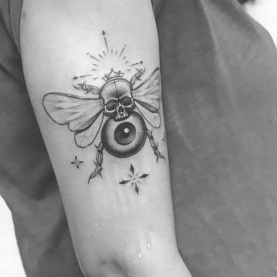 bee skull eye tattoo design woman outer bicep