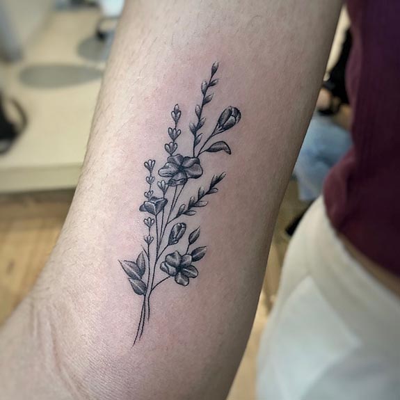 flowers with branches leaves tattoo woman lower bicep