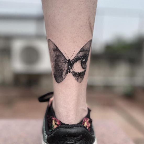 butterfly with one eye on a wing tattoo female lower calf