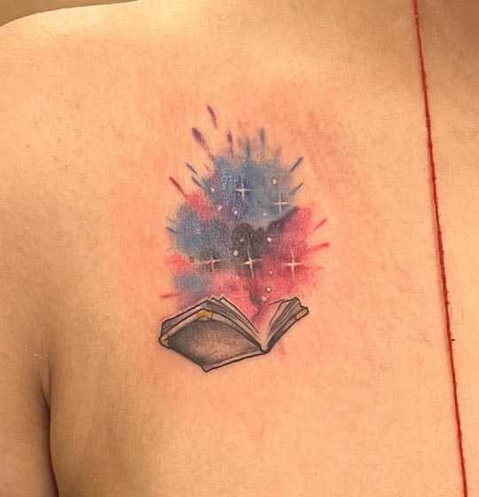 book with color splash tattoo design woman collarbone