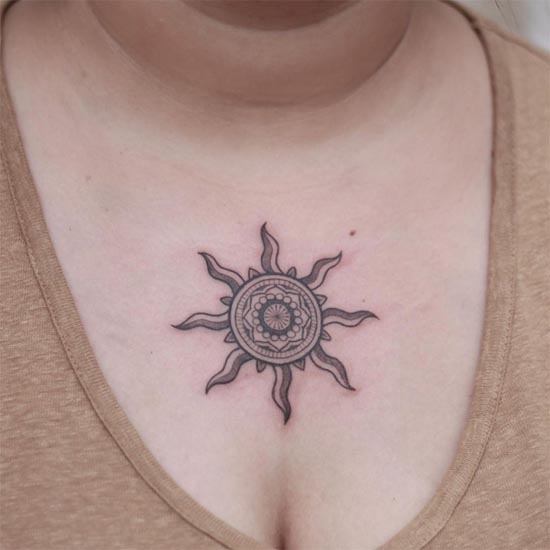 freehand sun small tattoo female in between chest black and grey