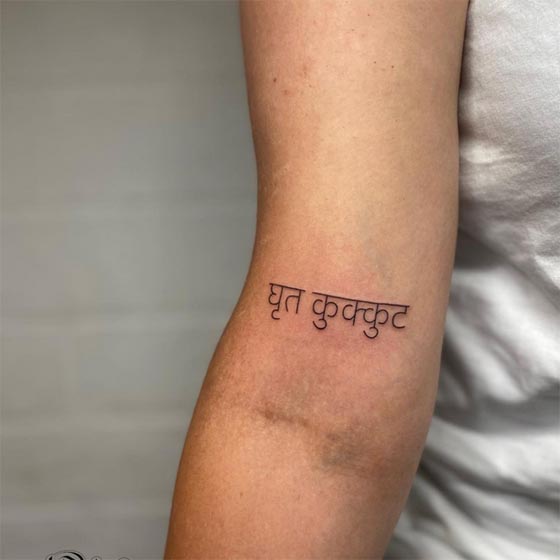 butter chicken in sanskrit text tattoo girl above inner elbow