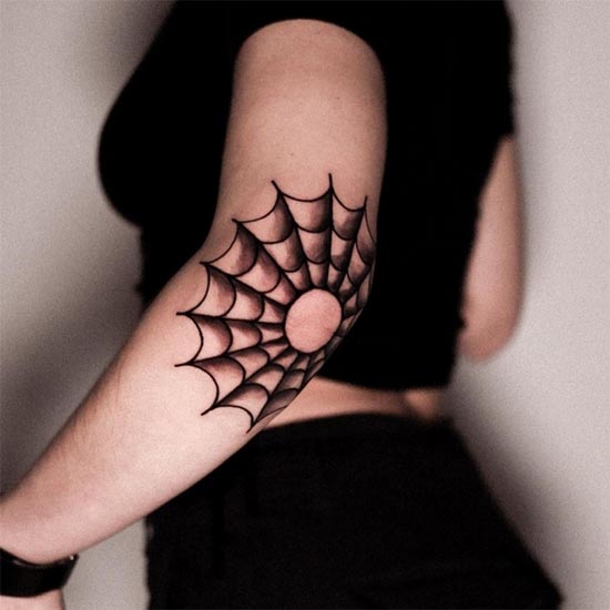 spider web classic round tattoo female hand around elbow