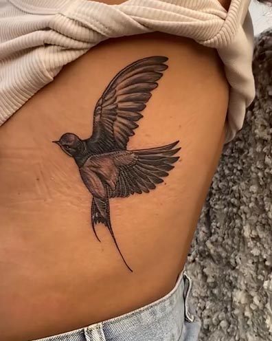 swallow bird large tattoo female upper rib black and grey