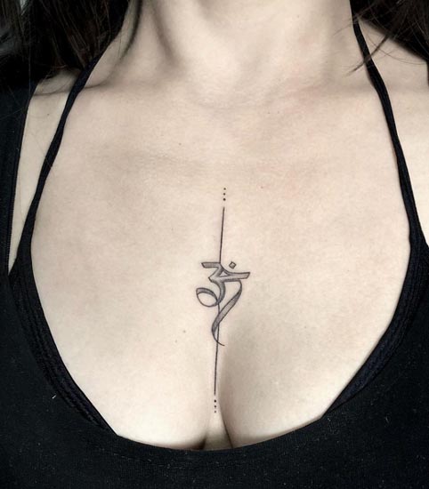 sanskrit lettering om symbol tattoo design female sternum