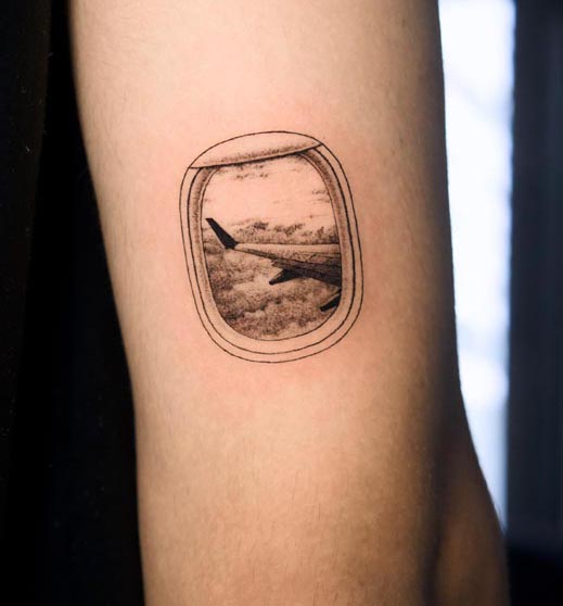 aeroplane window view showing clouds wing tattoo female tricep