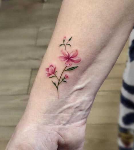 dainty cherry blossom pink leaves green tattoo design female side wrist