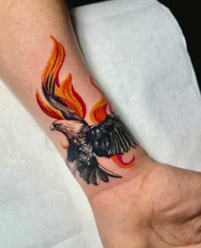 eagle with fire strokes from behind tattoo design man wrist